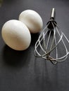 Whisk and two eggs on a black background Royalty Free Stock Photo