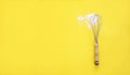 Whisk and white wheat flour on yellow background Royalty Free Stock Photo