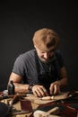 Whiskered shoemaker with making measurments in patterns at table in workshop