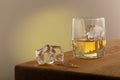 Whiskey or alcoholic beverage, with ie in a square formed designer glass. Sitting on an Oak table, with a backlighted gray surface