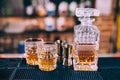 Whiskey bottle, crystal glasses and cocktail tools in modern bar, on counter