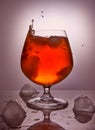 Whiskey, bourbon, brandy or cognac with ice on a pink background