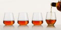 whiskey or brandy being poured into a glass from bottle on white background. Pouring whisky from a bottle Royalty Free Stock Photo