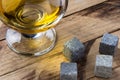 Whiskey cooling stones. Golden whiskey in glass with cooling stones on a wooden table