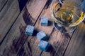 Golden whiskey in glass with cooling stones on a wooden table