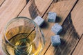 Golden whiskey in glass with cooling stones on a wooden table