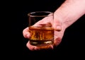 Whiskey glass in a hand of a man on black background, brandy in a glass Royalty Free Stock Photo