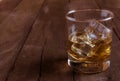 Whiskey in glass with ice cubes on wooden table