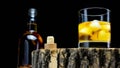 Whiskey with ice on a black background. Alcoholic elite drink in a glass on a wooden one. Liqueur with ice