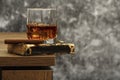 Whiskey with ice or brandy in a glass on a background of gray concrete on an old wooden table. Whiskey with ice in a glass. Whiske