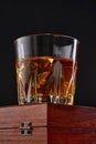 Whiskey with ice or brandy in glass with cigar on black background. Whisky with ice in glass. Whiskey or brandy. Selective focus