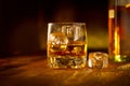 Whiskey with ice cubes. Glass of Whisky and the bottle on wooden table over dark background. Glass of rum alcohol close-up Royalty Free Stock Photo