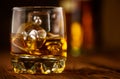 Whiskey with ice cubes. Glass of Whisky and the bottle on wooden table over dark background. Glass of rum alcohol close-up Royalty Free Stock Photo