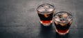 Whiskey with ice in a glass. Rum-Cola. Brandy. On a black wooden background. Royalty Free Stock Photo