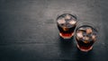 Whiskey with ice in a glass. Rum-Cola. Brandy. On a black wooden background. Royalty Free Stock Photo