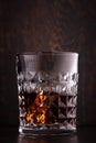 Whiskey with ice in glasses, rustic wood background