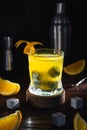 Whiskey orange juice cocktail in glass with natural cube stones and orange peel at black background