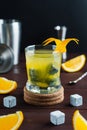 Whiskey cocktail in glass with natural cube stones and orange peel. Jagger and shaker at background