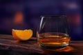 Whiskey drink glass with orange slice on wooden table on dark blurred bar background Royalty Free Stock Photo