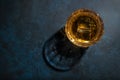 Whiskey, scotch or bourbon glass with ice on blue background with hard lights and shadows, top view, copy space