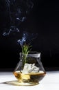 Whiskey, scotch or bourbon glass with rosemary, shard ice and smoke on black white background. Contemporary still life