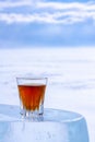 Whiskey in a small glass stands on a piece of ice. Royalty Free Stock Photo