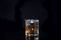 Whiskey splash from the fallen ice cube into glass with beverage isolated on black background Royalty Free Stock Photo