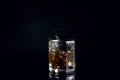 Whiskey splash from the fallen ice cube into glass with beverage isolated on black background Royalty Free Stock Photo