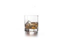 Whiskey splash from the fallen ice cube into glass with beverage on light background Royalty Free Stock Photo