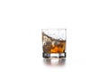 Whiskey splash from the fallen ice cube into glass with beverage on light background Royalty Free Stock Photo