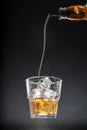 Whisky pouring into a glass on black background