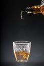 Whisky pouring into a glass on black background