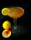 A whisky sour in a coupe glass with a lemon wagon wheel garnish on a dark background.