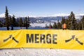 WHISTLER, BC, CANADA - FEB 4, 2023: Skiers on Blackcomb Mountain with a merge sign in the foreground.