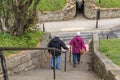 Elderly couple walk down decend old historic stone steps wearing jacket coats