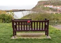 Empty park bench with roses attached as a memorial. View over seaside town and bay