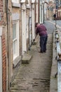 Old man uses a broom brush to sweep in street