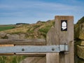 The white acorn National Trail sign on a weathered wooden gatepost shows the way of Hadrian`s Wall Path in the Northumberland