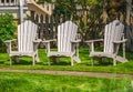 White Adirondack chair setting at the garden. Traditional curveback red wooden beach chair. Red Muskoka chairs in a park Royalty Free Stock Photo