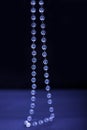 White agate stone chain on a blue and black background close-up Royalty Free Stock Photo