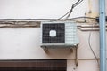 White air conditioning on the old wall of the house with the old wires of communication on the plastic drain pipe above the window Royalty Free Stock Photo