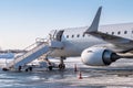 White airliner with passenger boarding stairs at the cold winter airport apron