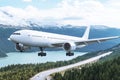 White airplane flying over a mountain range with a lake and a winding road in the foreground Royalty Free Stock Photo