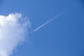 White airplane and its vapour trails on the background of a bright blue sky. Looking up at the sky. Plane flying high in the sky t