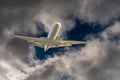 White airplane jet flying through a hole in dark dangerous and dramatic storm clouds