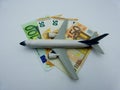 White airplane lands on a pile of Euro banknotes. Aviation concept.