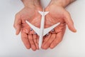 White airplane model in human hands. Airolane protection. Concept of aircraft industry, airline safety, security and