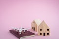 White airplane, Thai passport and wooden house model on pink background