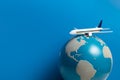 White airplane toy model with global world on blue background in airline business for travel tour international