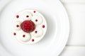 White airy cake with raspberry layer and raspberry berry lies on a white round plate next to a white cup, which stands on a white Royalty Free Stock Photo